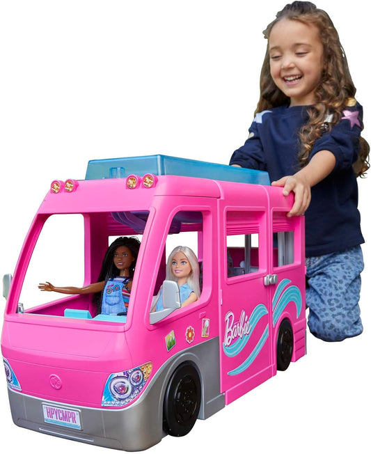 Child playing with pink Barbie Super Abenteuer-Camper vehicle toy featuring two Barbie dolls inside.